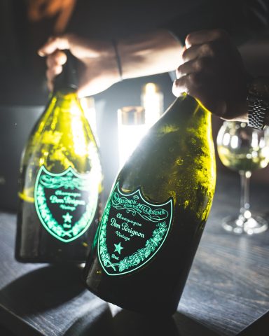 Zwei große Champagnerflaschen mit leuchtenden Etiketten auf einem Tisch.